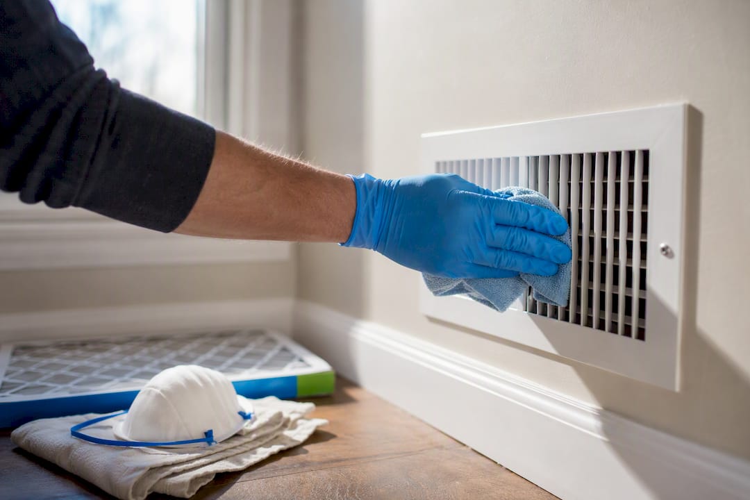 Gloved hand wiping a visible air register