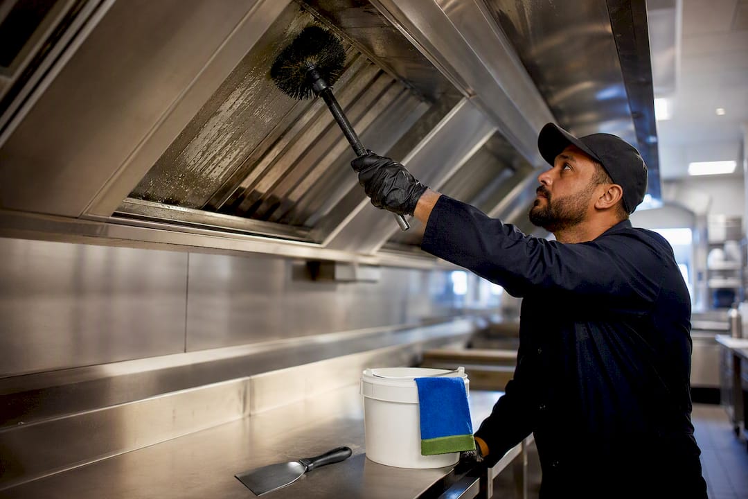 Technician cleaning commercial kitchen hood